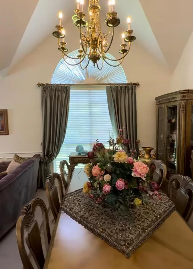 Gray tieback drapes beside white horizontal blinds below an arched dining room window.