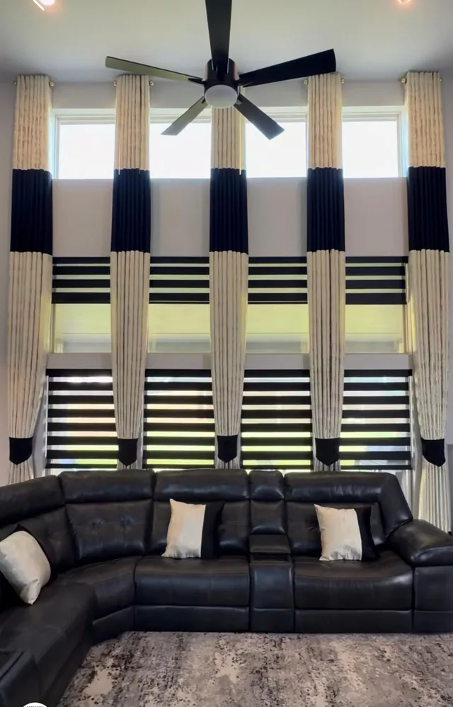Cream and navy drapes with zebra blinds showing alternating sheer and dark horizontal bands.