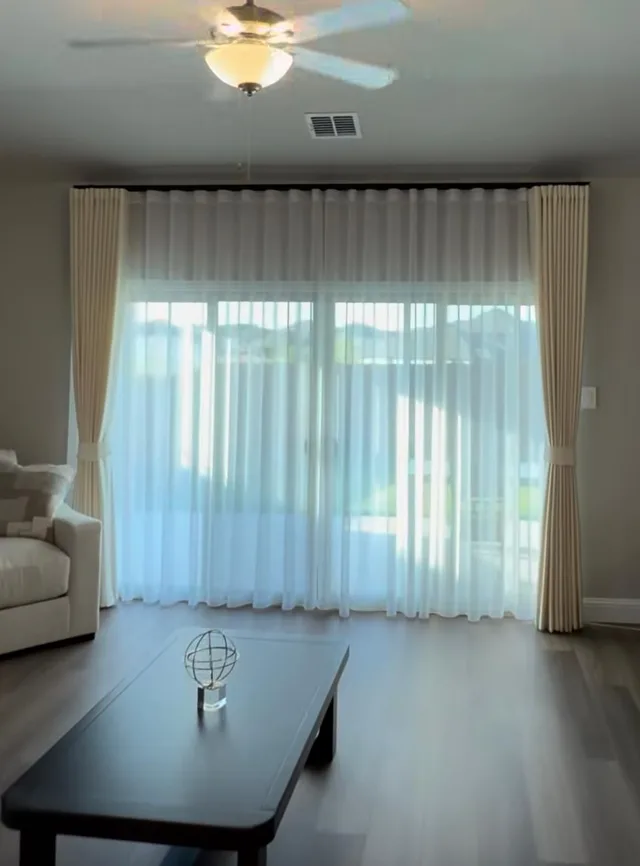 Ivory curtains tied back over white sheer panels in a living room.