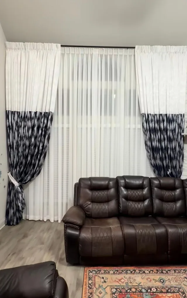 White curtains with navy patterned lower sections tied back over white sheers.
