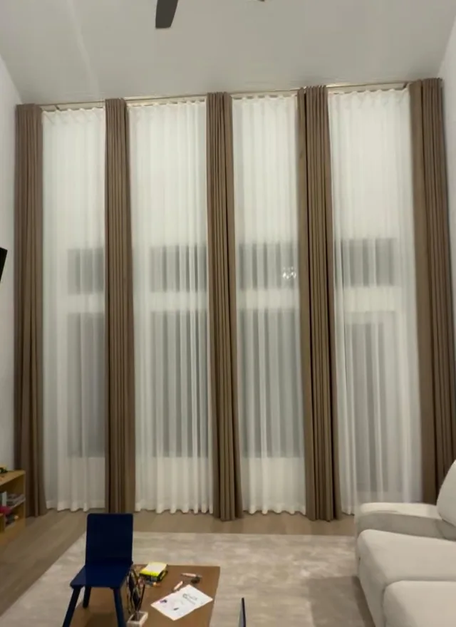 Full-height taupe drapery and white sheers in a family living room with a white sofa.