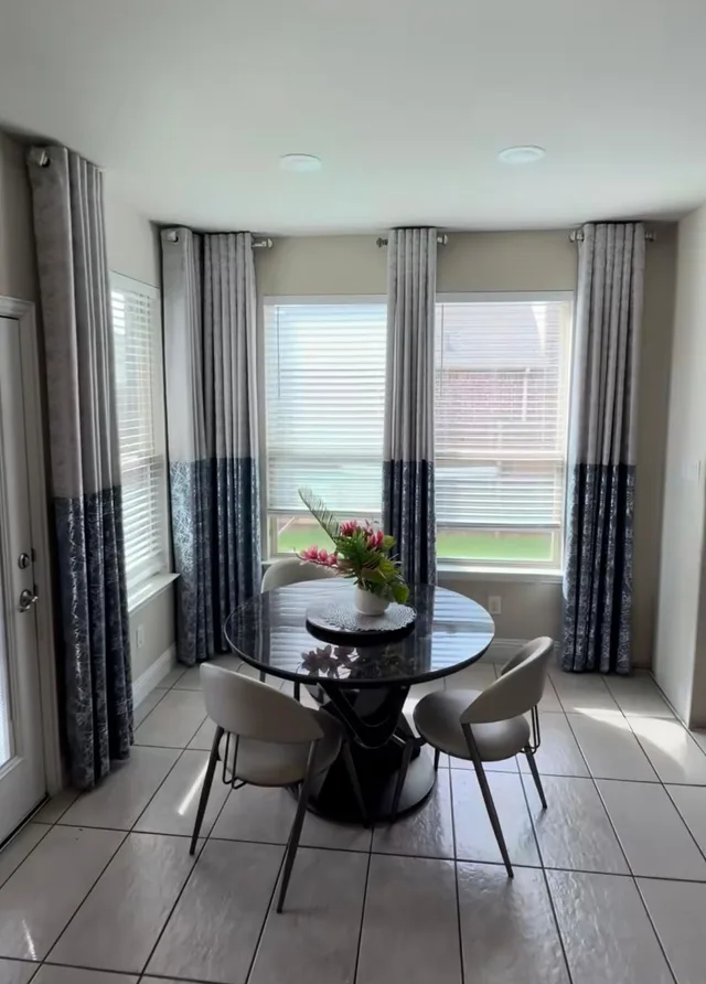 Gray and navy curtain panels paired with white blinds around a dining nook.