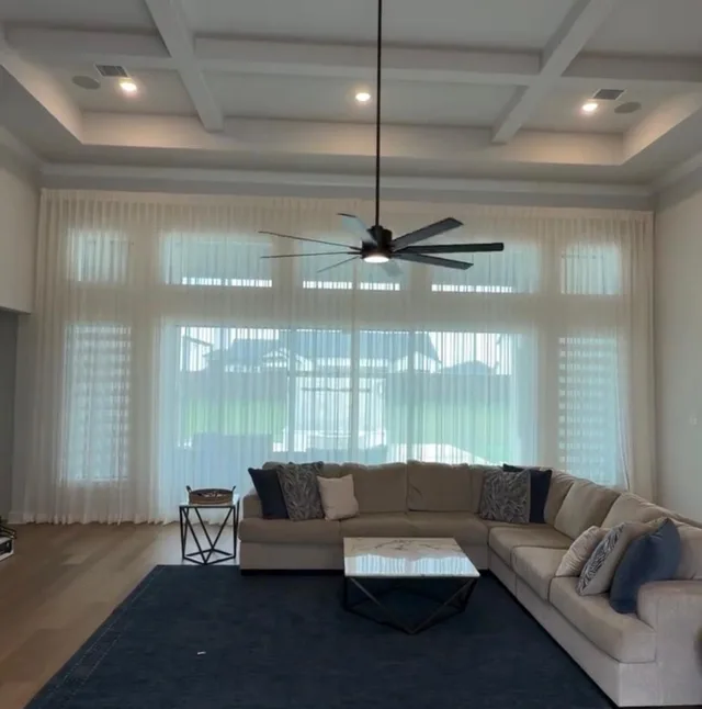 White floor-length sheer curtains across a wide living room window wall.